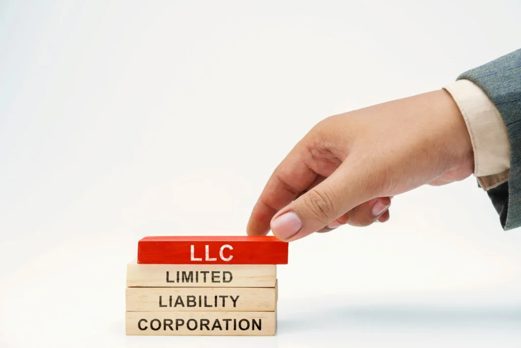 A hand stacking blocks that say LLC.